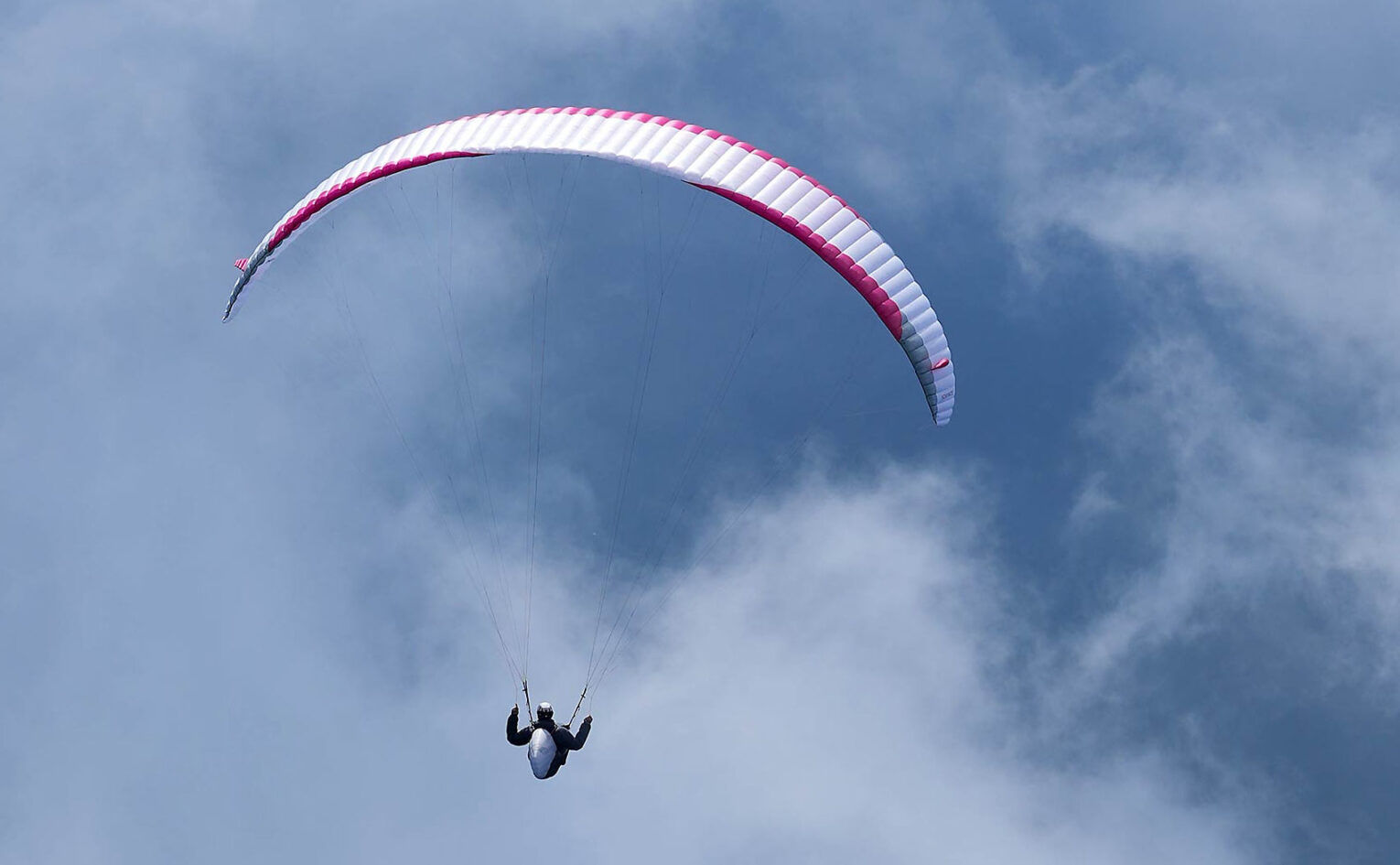 Paraglider flying above clouds