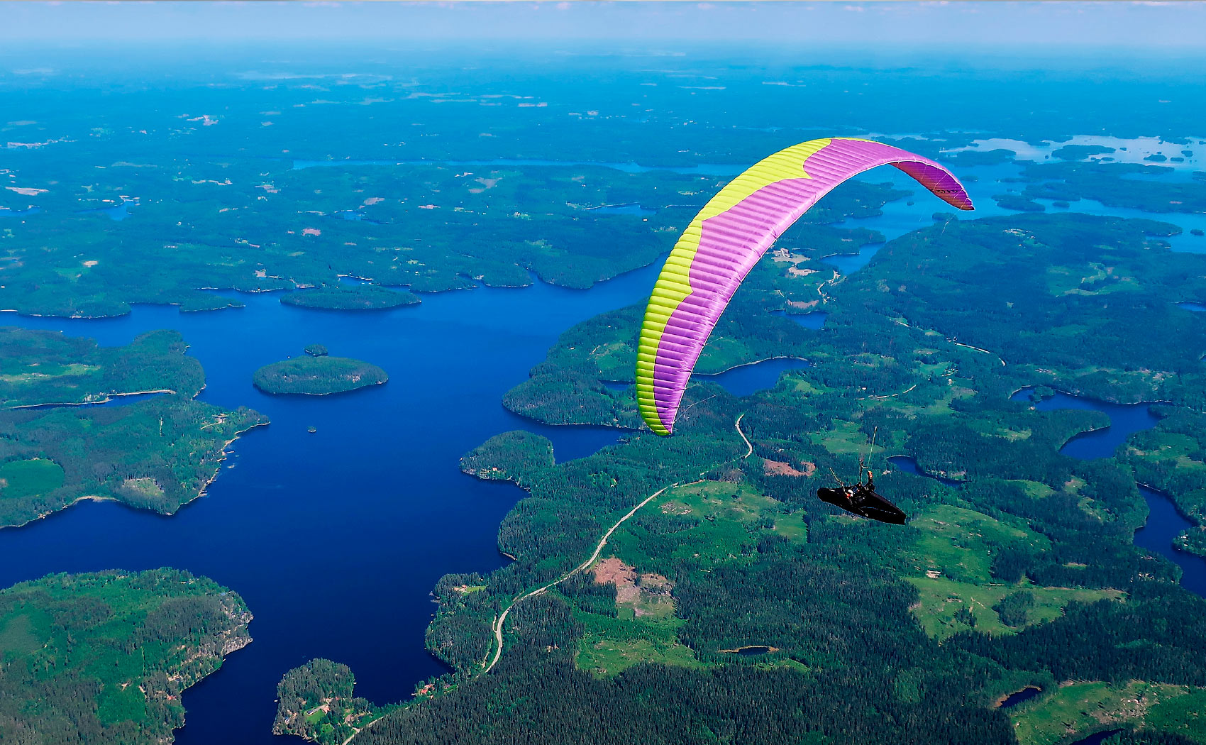 Paragliding in the flatlands of Finland with a view of lakes and forest

