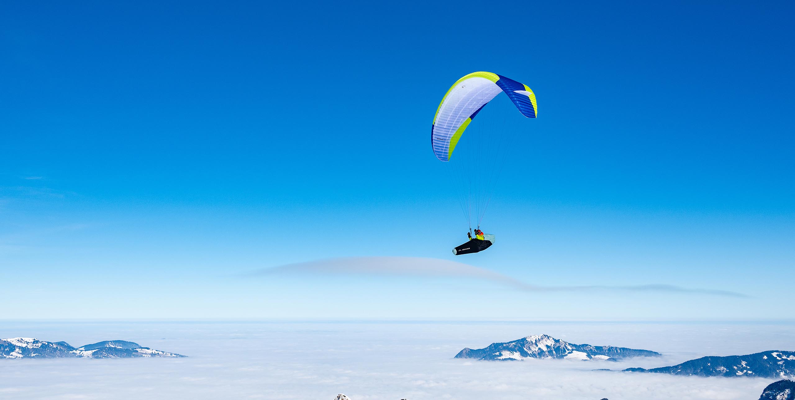 Paragliding wave. The smooth cloud indicates the top of the rising air in the wave. Unlike a cumulus which forms and dissipates quickly from convection, wave clouds can “stand” in the same place for a long time. Clouds form on the crests of the waves due to cooling and dissipate in the troughs due to warming. Photo: Adi Geisegger